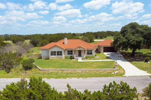 mediterranean / spanish house featuring fence, a tiled roof, a front yard, a chimney, and a garage