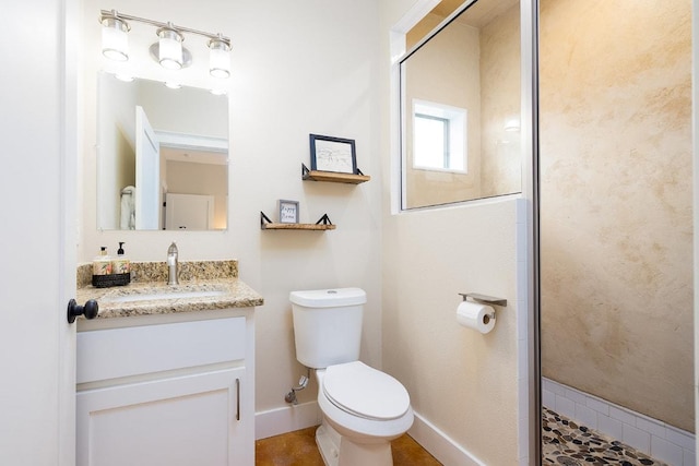 bathroom featuring baseboards, vanity, toilet, and a shower stall