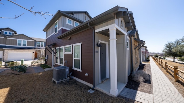 view of side of home with fence, central AC unit, and board and batten siding