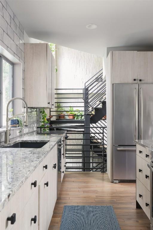 kitchen featuring light stone counters, freestanding refrigerator, light wood-style floors, and a sink