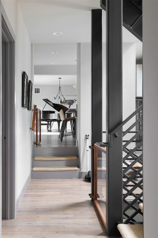 corridor with visible vents, an inviting chandelier, wood finished floors, and stairs