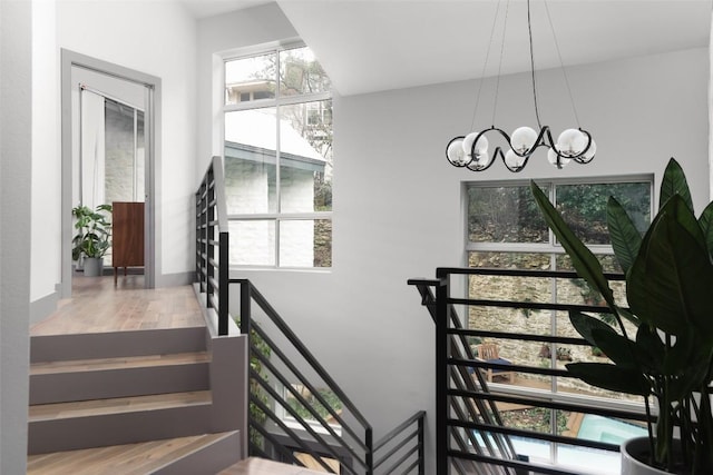 staircase featuring an inviting chandelier and wood finished floors