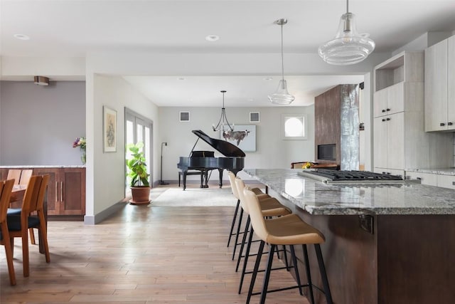 kitchen with visible vents, plenty of natural light, a breakfast bar, and light wood finished floors