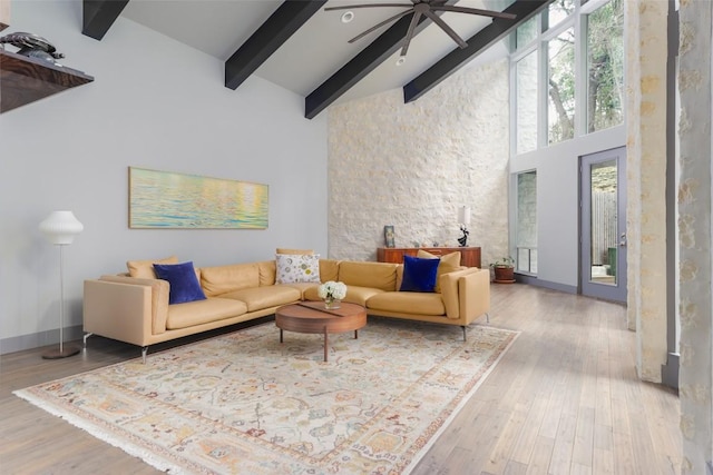 living area featuring wood finished floors, baseboards, high vaulted ceiling, ceiling fan, and beamed ceiling