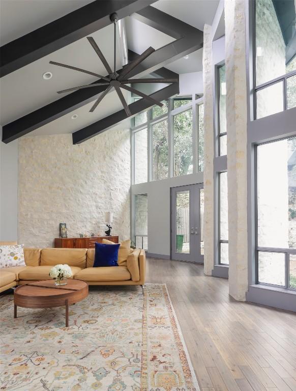 living room with beamed ceiling, wood finished floors, and a towering ceiling