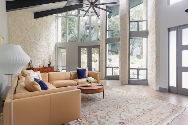 living room featuring french doors, beamed ceiling, and a towering ceiling