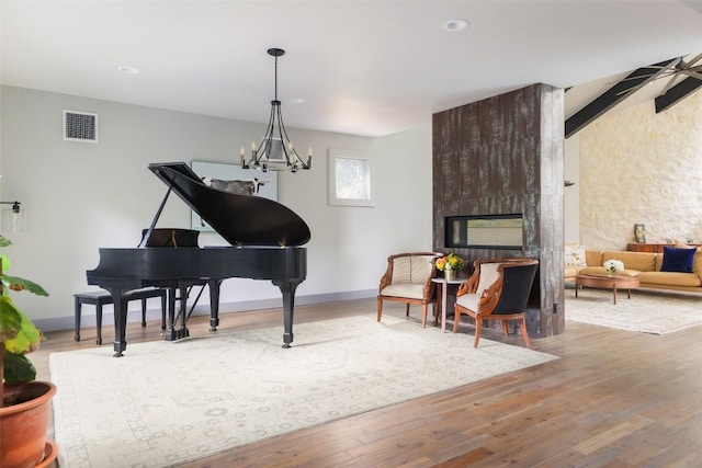 living area featuring beamed ceiling, wood finished floors, visible vents, and baseboards