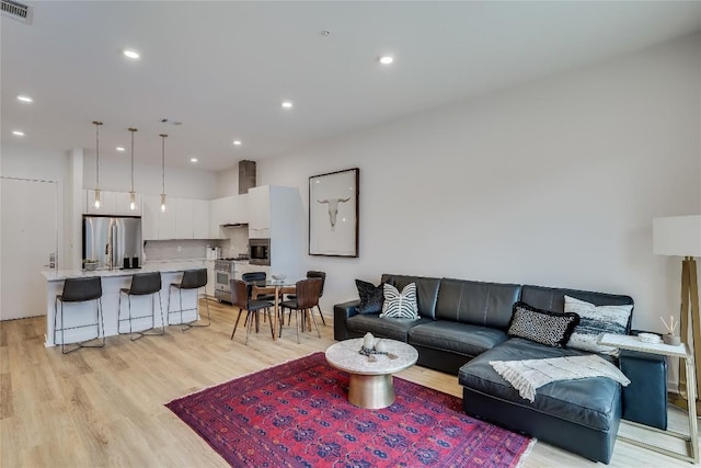 living area featuring light wood-style flooring, recessed lighting, and visible vents