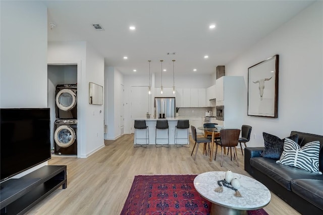 living room featuring light wood finished floors, visible vents, recessed lighting, and stacked washer and clothes dryer