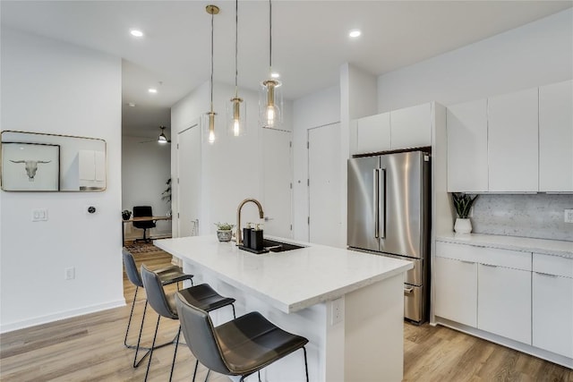 kitchen featuring white cabinets, light wood finished floors, modern cabinets, and freestanding refrigerator