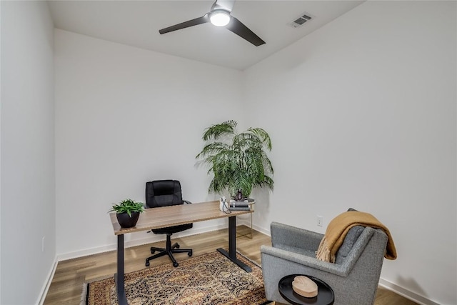 office area with visible vents, a ceiling fan, baseboards, and wood finished floors