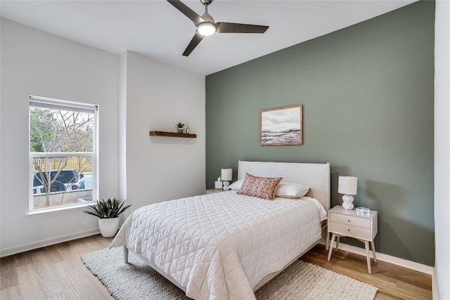 bedroom featuring ceiling fan, baseboards, and wood finished floors