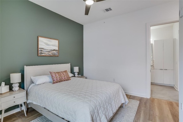 bedroom featuring visible vents, baseboards, ceiling fan, and wood finished floors