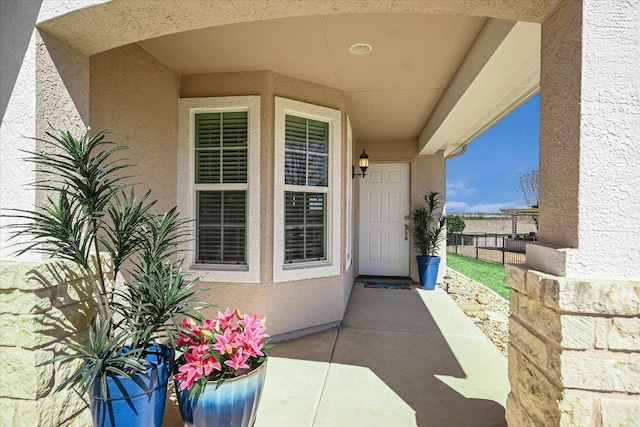 doorway to property featuring fence and stucco siding