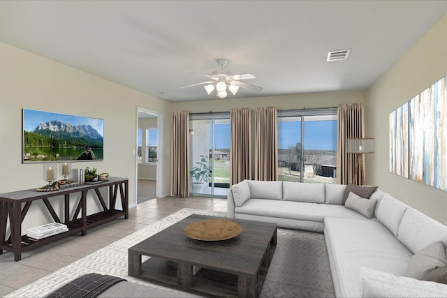 living room with light tile patterned flooring, visible vents, baseboards, and ceiling fan