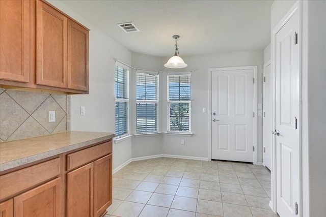 kitchen featuring pendant lighting, light countertops, light tile patterned floors, decorative backsplash, and baseboards