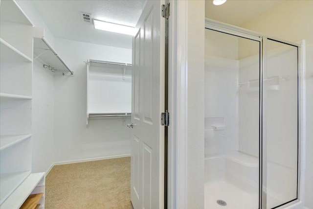 full bath featuring a spacious closet, visible vents, a shower stall, and a textured ceiling