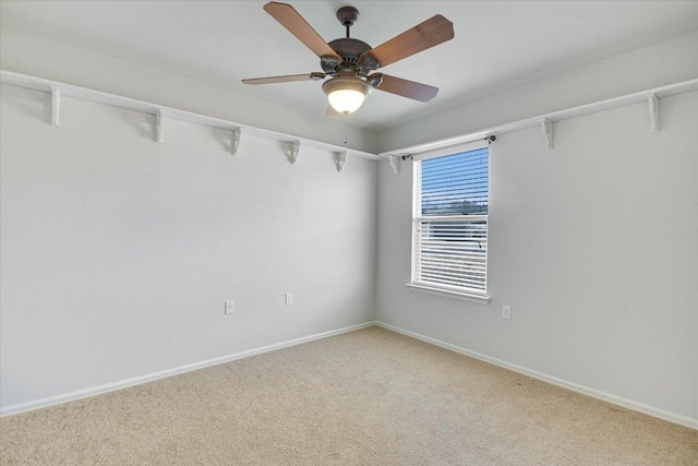 spare room with light colored carpet, a ceiling fan, and baseboards