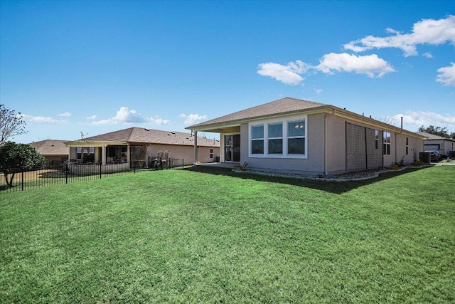 rear view of property featuring a lawn, fence, and stucco siding