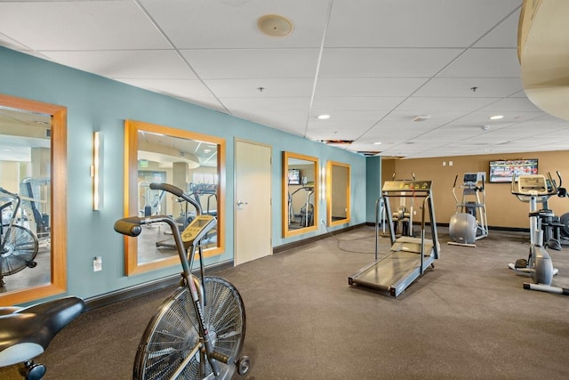 gym with a paneled ceiling and baseboards