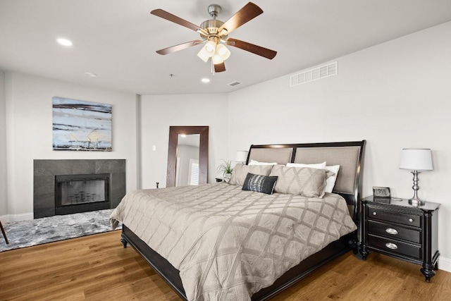 bedroom with visible vents, wood finished floors, and a fireplace