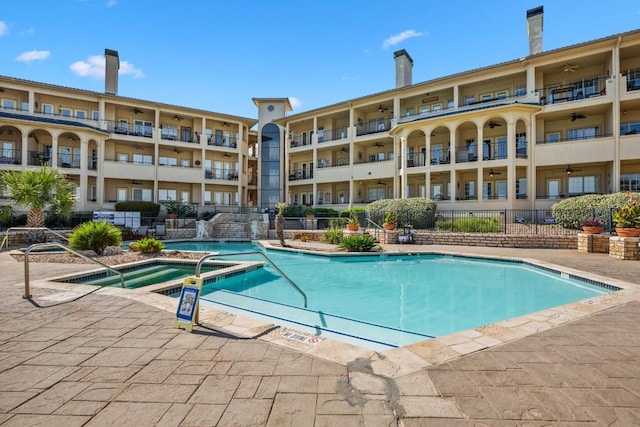 community pool with a patio area, a community hot tub, and fence