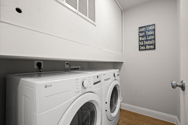 laundry area featuring washer and dryer, baseboards, wood finished floors, and laundry area