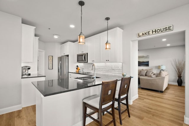 kitchen featuring a sink, light wood-style flooring, appliances with stainless steel finishes, and white cabinets