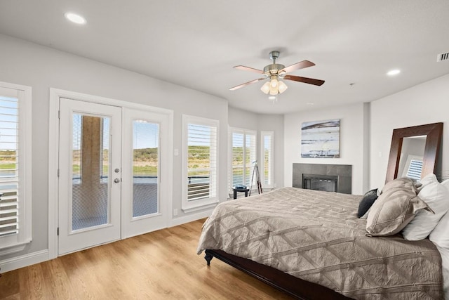 bedroom featuring access to outside, recessed lighting, light wood finished floors, and a tile fireplace