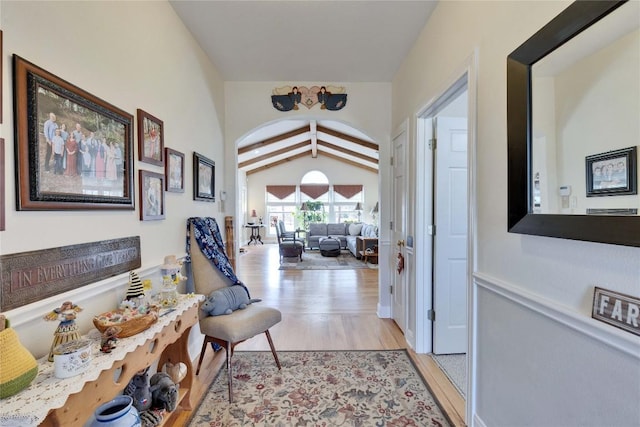 corridor with light wood-style flooring and vaulted ceiling with beams