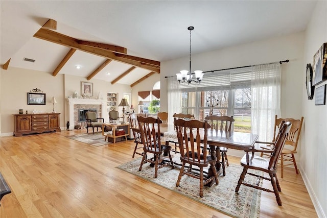 dining room with visible vents, plenty of natural light, a fireplace, and vaulted ceiling with beams