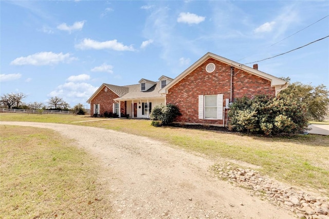 view of front of house featuring driveway, brick siding, a front yard, and fence