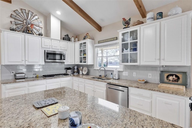 kitchen with backsplash, appliances with stainless steel finishes, vaulted ceiling with beams, and white cabinetry