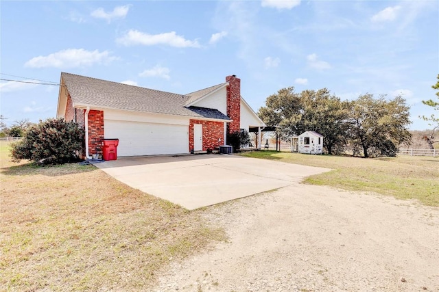 681 Leisure Ln, Cedar Creek, TX 78612 - view of home's exterior with concrete driveway, an attached garage, brick siding, an outdoor structure, and a chimney