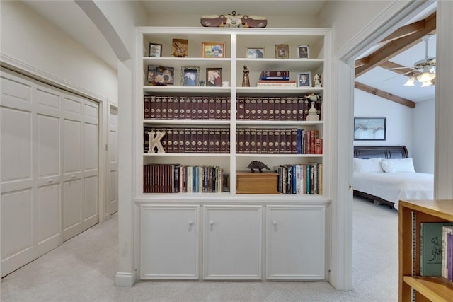 interior space featuring beamed ceiling, a ceiling fan, arched walkways, and carpet floors