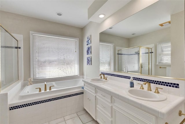 full bath featuring double vanity, a stall shower, a garden tub, and a sink