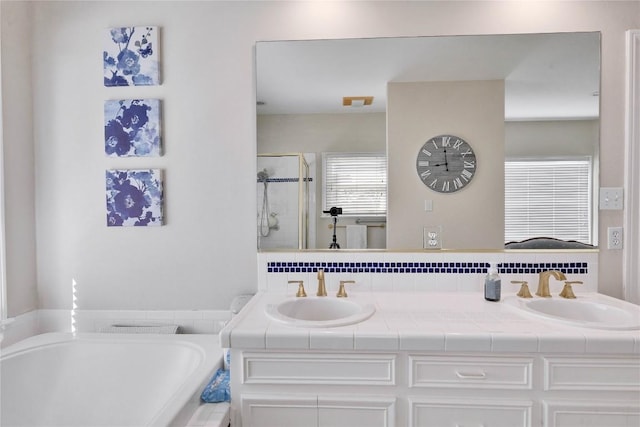 full bathroom with a bath, a shower stall, double vanity, and a sink