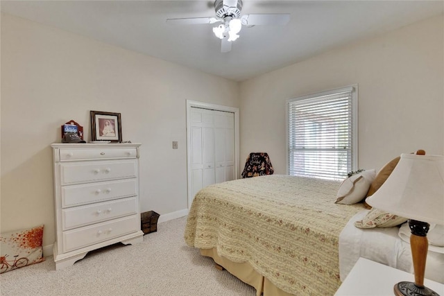 bedroom with light colored carpet, ceiling fan, baseboards, and a closet