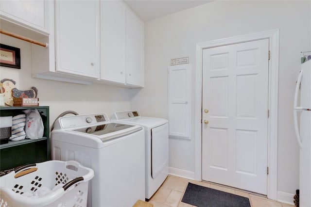 laundry room with washing machine and clothes dryer, baseboards, light tile patterned floors, and cabinet space