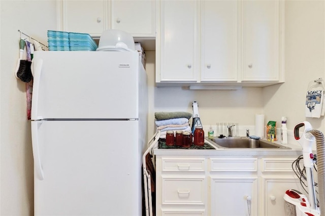 kitchen featuring white cabinets, a sink, light countertops, and freestanding refrigerator