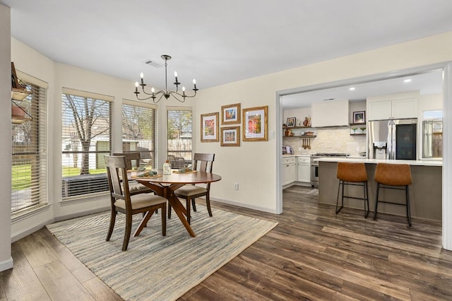 dining space featuring dark wood finished floors, recessed lighting, baseboards, and an inviting chandelier