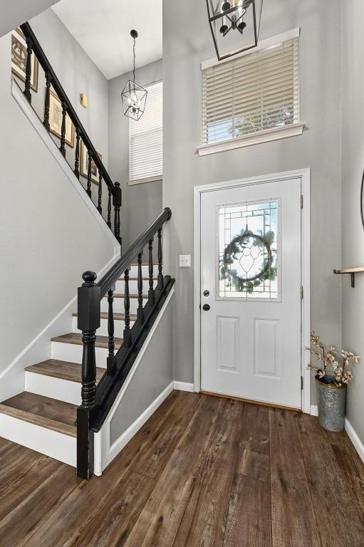 foyer entrance featuring a healthy amount of sunlight, stairs, a high ceiling, and wood finished floors