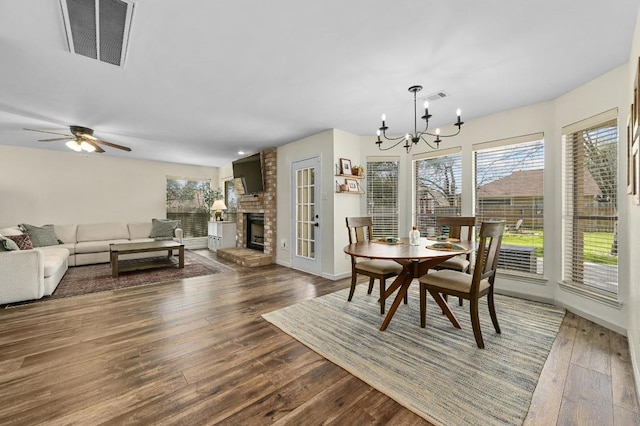 dining room with visible vents, a brick fireplace, baseboards, and hardwood / wood-style floors