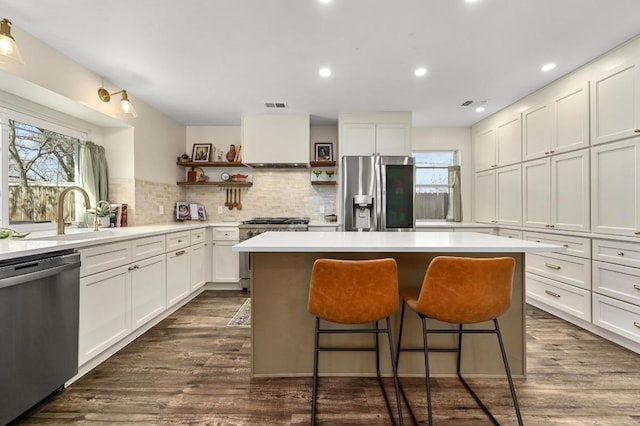 kitchen with visible vents, open shelves, a center island, appliances with stainless steel finishes, and a sink