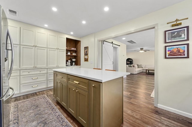 kitchen featuring visible vents, light countertops, a barn door, freestanding refrigerator, and dark wood-style floors