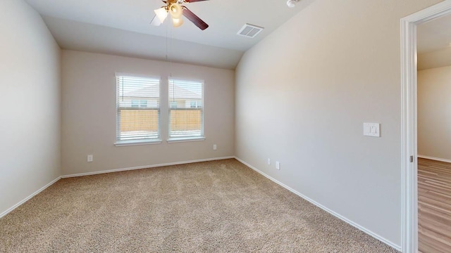 spare room with visible vents, a ceiling fan, baseboards, lofted ceiling, and light colored carpet