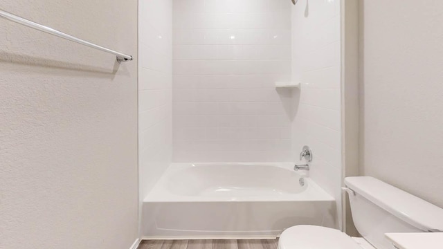 bathroom featuring toilet, wood finished floors, and shower / bathtub combination