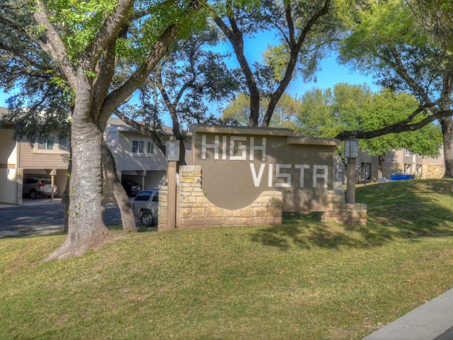 community / neighborhood sign featuring a carport and a lawn