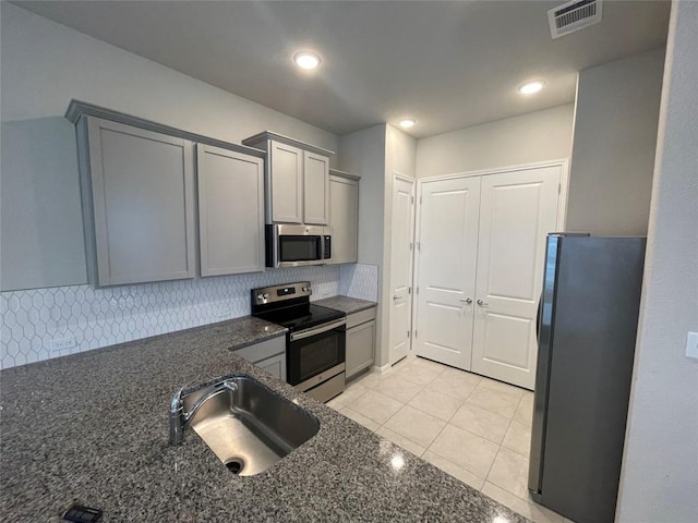 kitchen with visible vents, light tile patterned flooring, gray cabinets, a sink, and stainless steel appliances