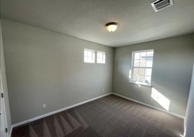 unfurnished room featuring dark colored carpet, visible vents, baseboards, and a textured ceiling